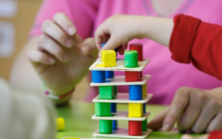 Children constructing a tower with small blocks and plates. 